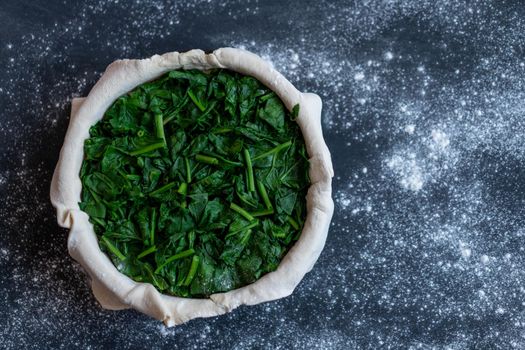 raw spinach pie preparation Standing wooden table background Copy space for text