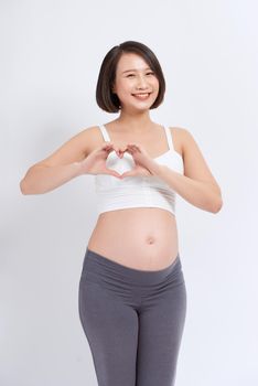 happy pregnant woman holding hands in heart shape on belly