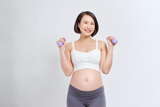 Pregnant woman training with dumbbells