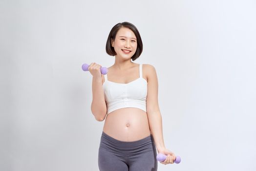 Pregnant woman exercising with dumbbells , isolated on white