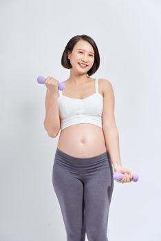 Asian pregnant woman do exercise, standing and lifting dumbbells, sportive pregnancy motherhood concept