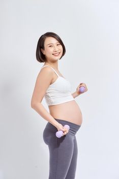 Asian pregnant woman do exercise, standing and lifting dumbbells, sportive pregnancy motherhood concept