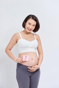 Closeup photo of pregnant with question mark drawn on post-it sticker on belly