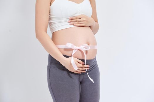 Pregnant belly with pink ribbon - isolated over a white background.