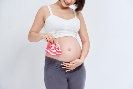 A portrait of a Pregnant woman with a pair of pink knit baby shoes