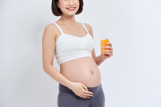 Young pregnant woman drinking orange juice with pleasure