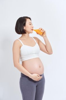 Charming pregnant woman holding a glass of orange juice while standing