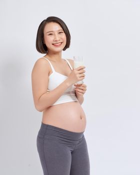 Pregnant young asian woman with a glass of milk in hand.