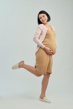 Image of a beautiful young pregnant emotional woman posing isolated over white background.