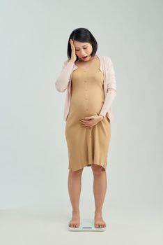 Pregnant woman standing on scales at home. Pregnancy weight gain concept