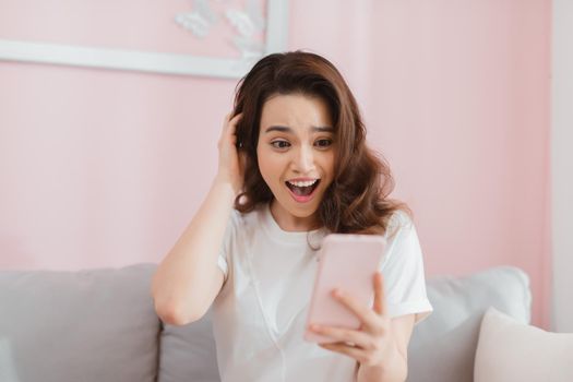 Young asian woman looking at surprised mobile with surprise expression showing emotion looking at message
