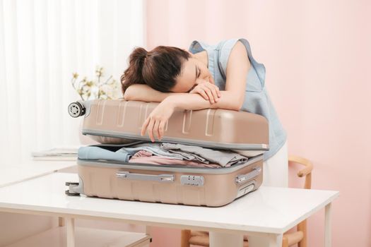 Woman trying to fit all clothing to packing her suitcase before vacation