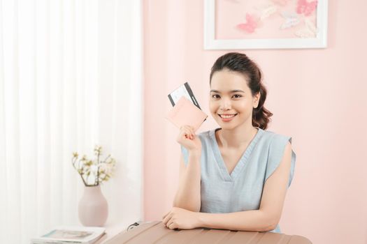 Travel concept. Woman holding passport and showing thumb up with suitcase nearby