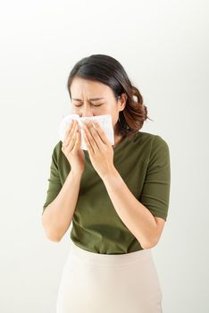 Woman with a cold blowing her runny nose with tissue