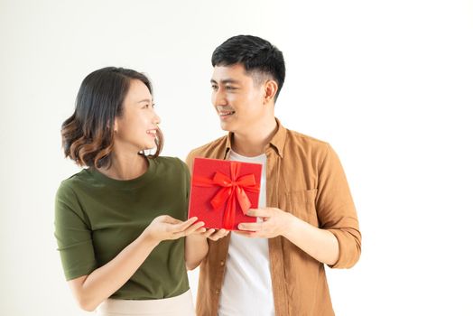 Portrait of happy couple in casual wear standing, holding box with present and looking at camera together