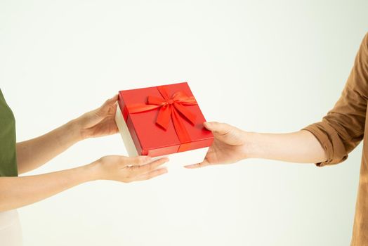 Close-up of man giving red gift box to woman over white background