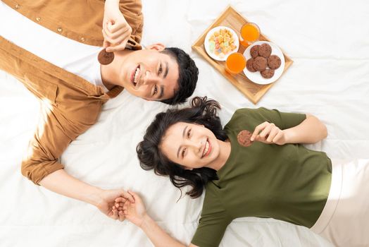 Romantic couple having breakfast lying in the bed at home