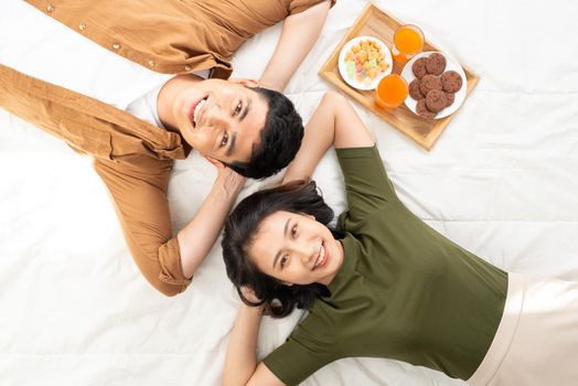 Cute couple having breakfast in bed in the bedroom.