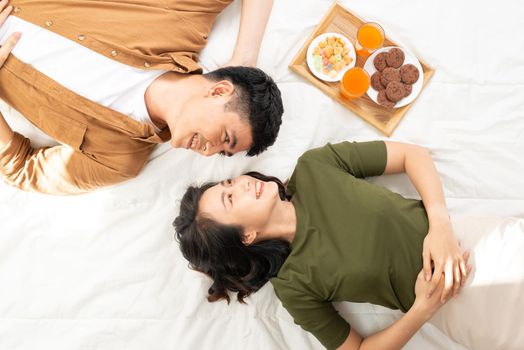 Romantic couple having breakfast lying in the bed at home