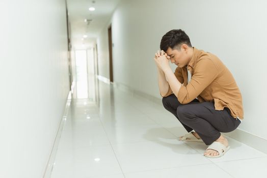 depressed man who lost faith sitting alone in a corridor