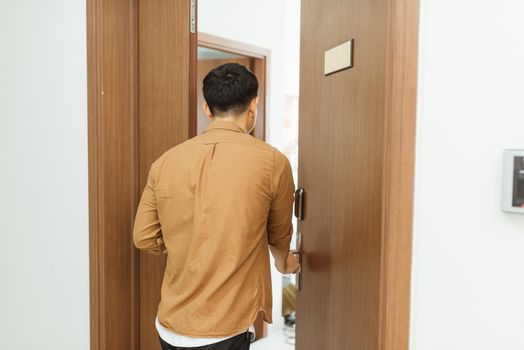 Man coming home from work and opening door of apartment