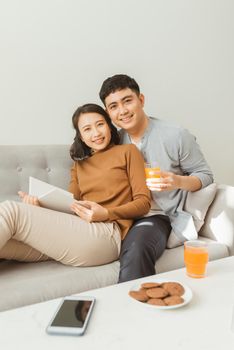 Attractive couple reading book on the sofa at home in living room