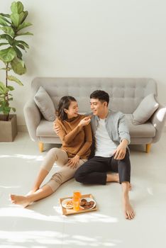 Couple sit on living room floor together eating