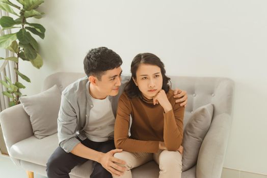 Young asian couple quarreling at home, woman offended. Family relationship difficulties concept, copy space