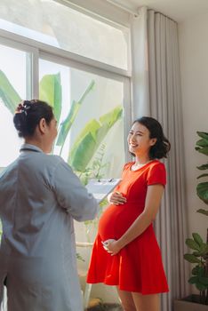 Doctor talks with the pregnant woman near window
