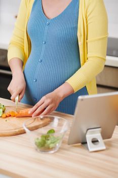 Young pregnant woman preparing healthy food with fruit and vegetables