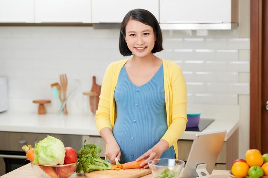 Young pregnant woman preparing healthy food with fruit and vegetables