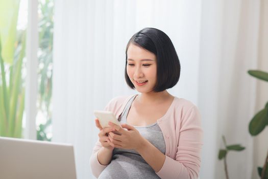 Pregnant Businesswoman Reading Text Message In Office