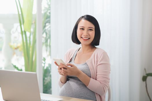 Young pregnant woman working in home office