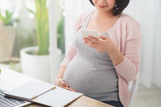 Pregnant Businesswoman Reading Text Message In Office