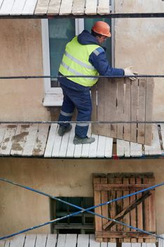 A builder installs wooden scaffolding to renovate an old house. Preparing to renovate the facade of an old house