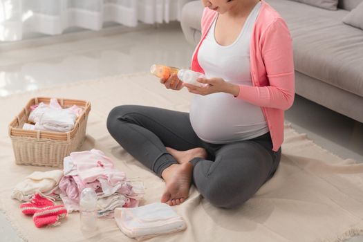 Asian mother preparing little clothes for new baby when sitting on the floor