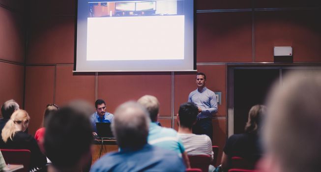 Speaker giving a talk in conference hall at business event. Unrecognizable people in audience at conference hall. Business and Entrepreneurship concept.