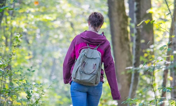 Young woman is walking through the forest, spring time