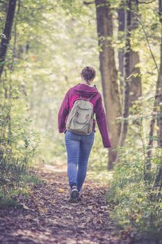 Young woman is walking through the forest, spring time