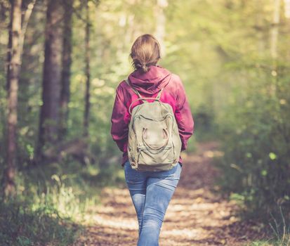 Young woman is walking through the forest, spring time