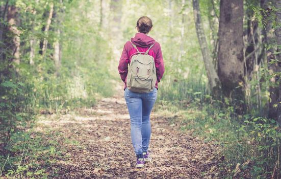 Young woman is walking through the forest, spring time