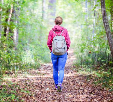Young woman is walking through the forest, spring time