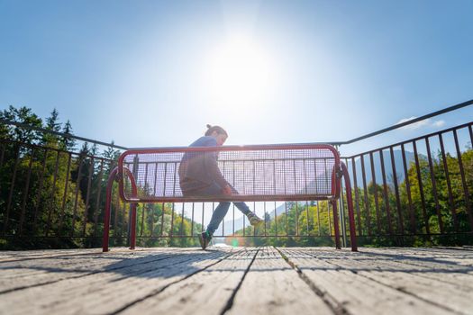 Young woman is sitting on bench, enjoying the view over a river