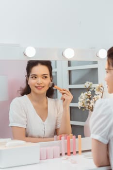 Young beautiful woman making make-up near mirror