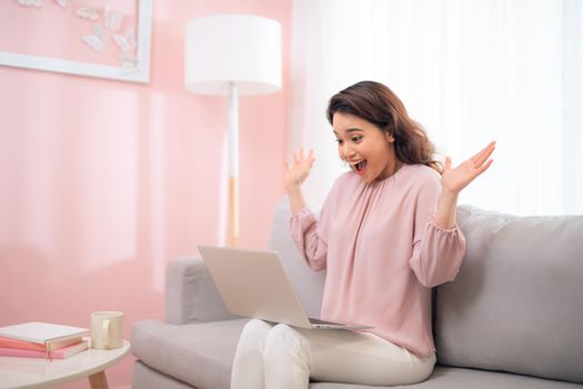 Excited young asian woman lifestyle image using laptop computer