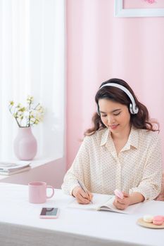 Focused woman wearing headphones write notebook