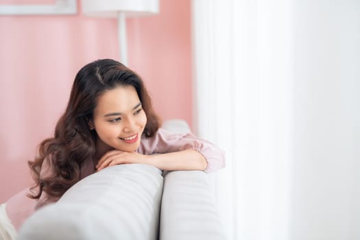 Beautiful young Asian woman relaxing on sofa.