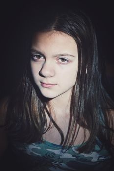 Facial portrait of cute teenage girl with long hair. Vertical shot, dark background. Toning