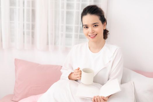 Beautiful woman reading a book on the bed in the morning