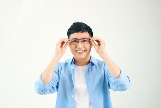 Closeup of friendly guy wearing eyeglasses. Young asian man adjusting glasses and staring at camera through lens. Vision and eye care concept